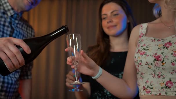 Snygg man häller champagne i glas med två sexiga tjejer. — Stockvideo