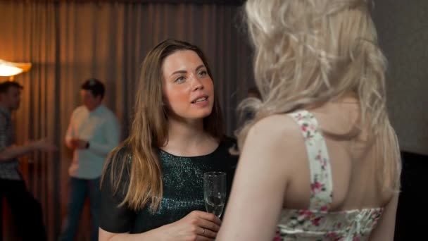 Two girls gossiping with glasses of champagne — Stock Video