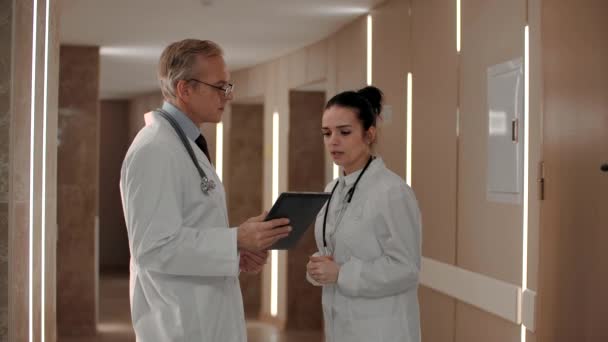 Two therapists discuss the diagnosis of the patient in the corridor of the hospital. — Stock Video