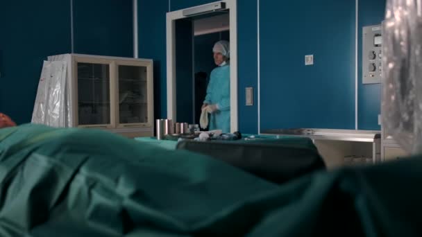 Zwei professionelle Chirurgen in Uniformen, Handschuhen, Masken und Mützen betreten den Operationssaal. — Stockvideo