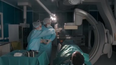 Modern ameliyathanede hastaların yanında cerrahlar konuşuyor.