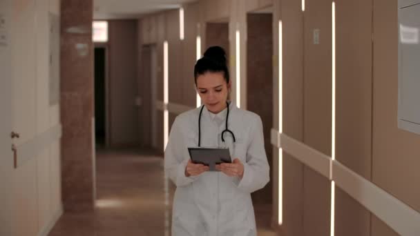 Дружелюбная женщина-врач ходит по больничному коридору — стоковое видео
