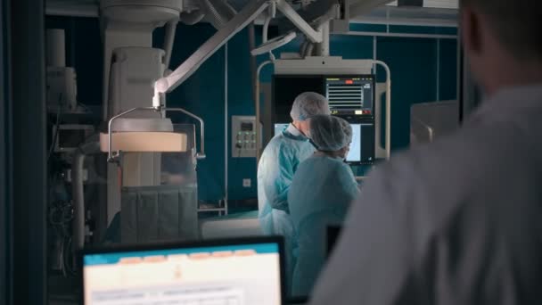 Врач наблюдает за операцией через окно в лаборатории — стоковое видео