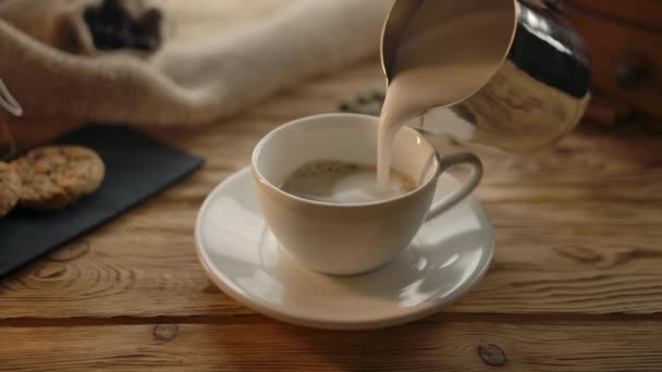 Häll skummad mjölk i kaffekopp i mysiga café — Stockvideo