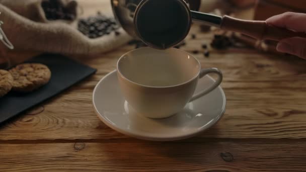 Жіноча рука наливає каву з Cezve на каву в чашку — стокове відео