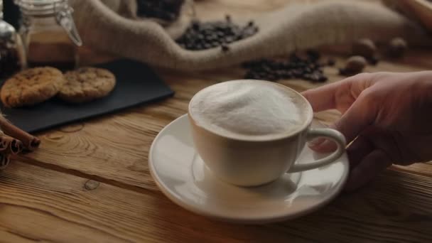 Pessoa irreconhecível coloca uma xícara de cappuccino na mesa — Vídeo de Stock