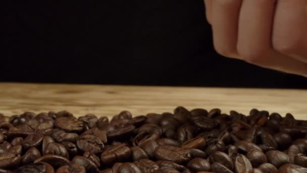 Vrouwen hand strooit koffiebonen op de tafel — Stockvideo