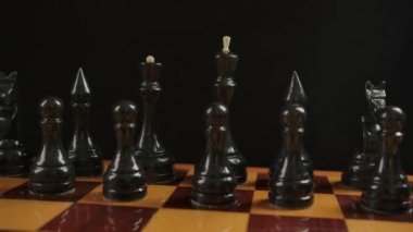 Başlangıç pozisyonunda dama tahtasındaki tahta siyah satranç taşlarının geniş açılı görüntüsü
