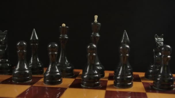 Breite Aufnahme schwarzer Holzschachfiguren auf einem Schachbrett in der Ausgangsposition — Stockvideo