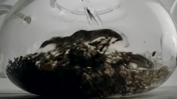 Verser de l'eau bouillante dans une théière transparente de la bouilloire 