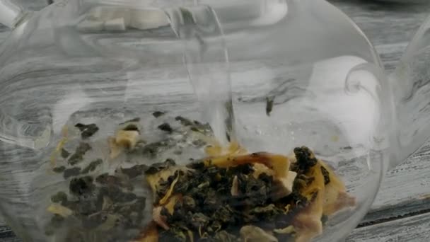 Kookwater in het brouwsel van witte thee met fruit in een glazen theepot gieten — Stockvideo