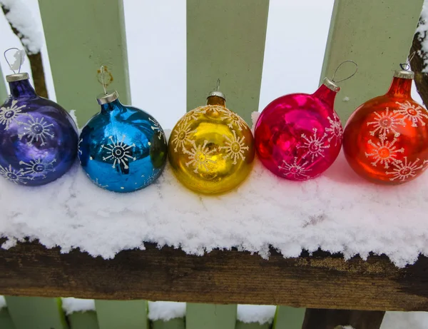 Cinco bolas de Navidad multicolores en la nieve . — Foto de Stock