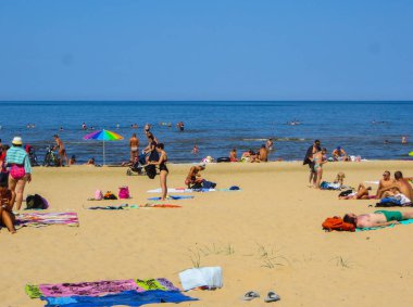 Jurmala, Letonya - 29 Temmuz 2018: İnsanlar Letonya 'nın Jurmala tatil beldesindeki Baltık Körfezi plajında güneşli bir bahar gününün tadını çıkarıyorlar.