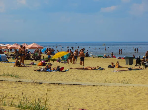 Jurmala, Letonia - 29 de julio de 2018: La gente disfruta del soleado día de primavera en la playa del golfo del mar Báltico en Jurmala resort, Letonia . — Foto de Stock