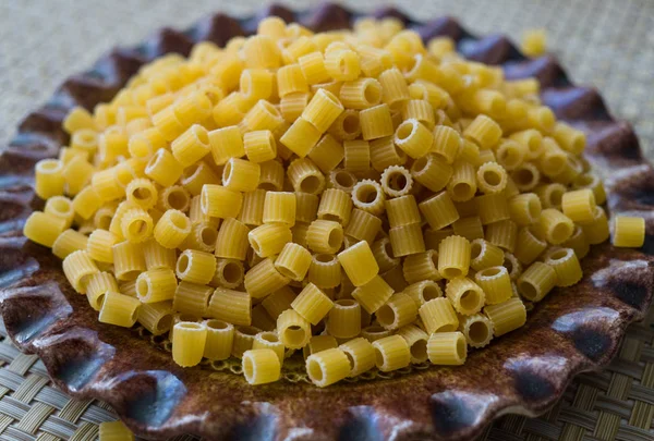 Pasta hecha de harina, esparcida en un plato, sobre una mesa . —  Fotos de Stock