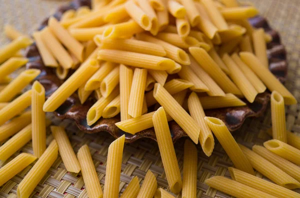 Pasta made from flour, scattered on a plate, on a table. — Stock Photo, Image