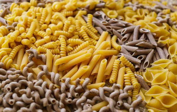 Fideos, pasta de diferentes tipos, esparcidos en la mesa . —  Fotos de Stock