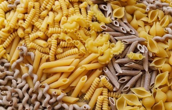 Fideos, pasta de diferentes tipos, esparcidos en la mesa . —  Fotos de Stock