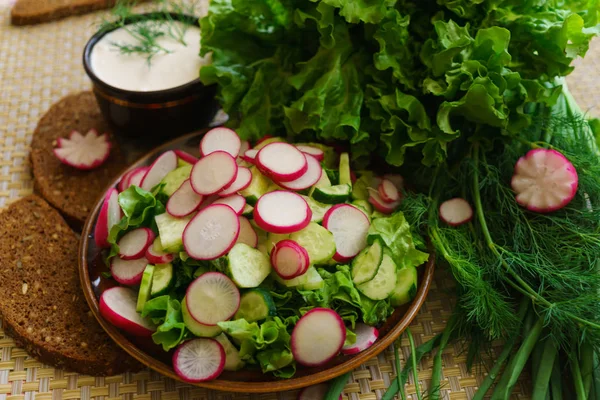 Ensalada cocida de pepino, rábano y hierbas, sazonada con crema agria . — Foto de Stock