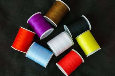 Koyu bir arkaplanda çok renkli iplik makaraları