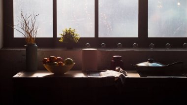 Sabah. Pencerenin yanında masada meyve. 