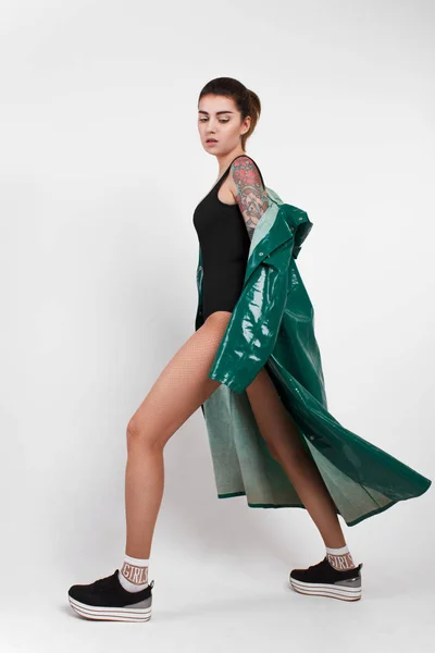 Yeşil yağmurluk elinde dövme olan genç moda kadın portresi