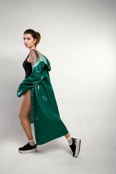 Yeşil yağmurluk elinde dövme olan genç moda kadın portresi