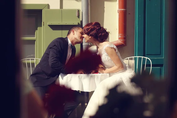 Romantic bridal couple kissing at a table — Stock Photo, Image