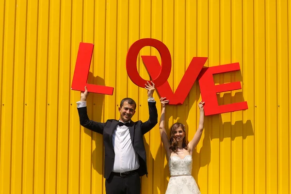Noiva e noivo se divertindo com letras de amor — Fotografia de Stock
