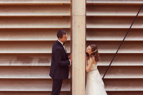 Mariée et marié s'amuser à côté de mur dépouillé — Photo