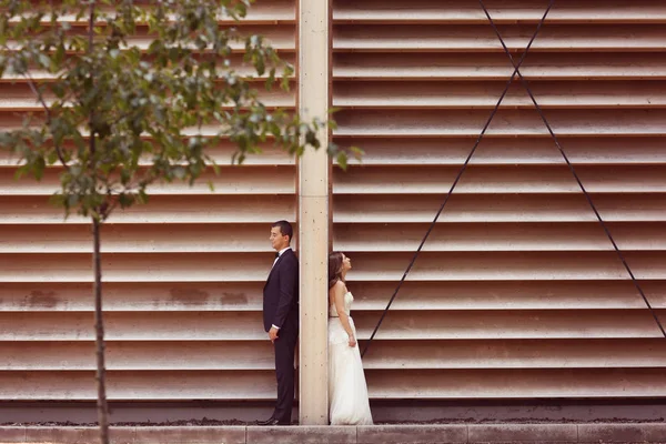 Mariée et marié stading dos à dos près de mur dépouillé — Photo