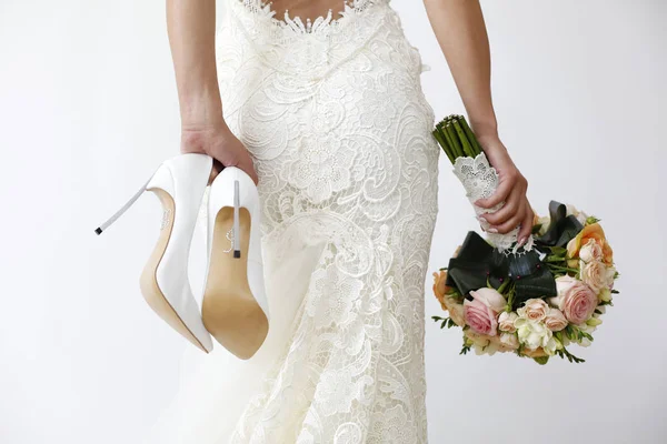 Prachtige bruid met schoenen en een boeket op geïsoleerde achtergrond — Stockfoto