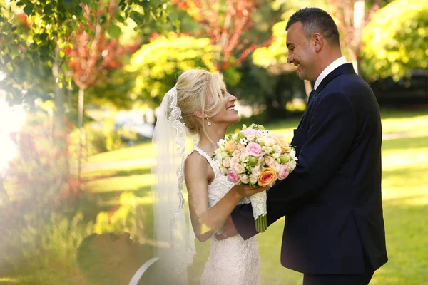 Alegre pareja nupcial abrazándose en la naturaleza — Foto de Stock