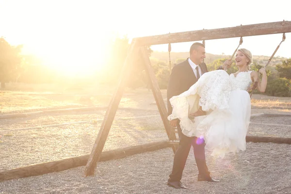 Casal de noivas alegre se divertindo no balanço — Fotografia de Stock