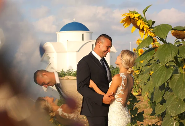 Bruden och brudgummen embracing nära solrosor — Stockfoto