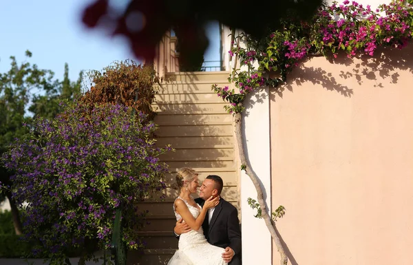 Freudiges Brautpaar umarmt sich in der Nähe bunter Blumen — Stockfoto