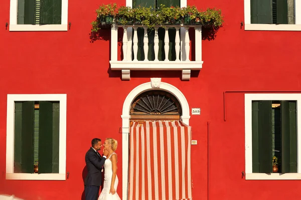 Невеста и жених позируют перед красным домом — стоковое фото