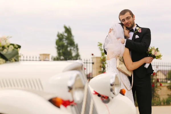 Bride and groom embracing near retro car — Stock Photo, Image