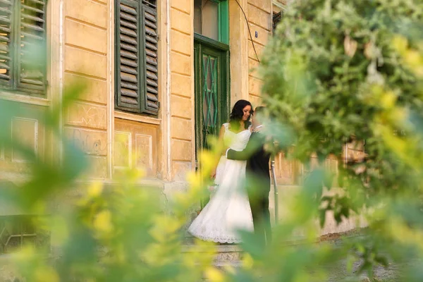 Bruden och brudgummen embracing nära gamla hus — Stockfoto