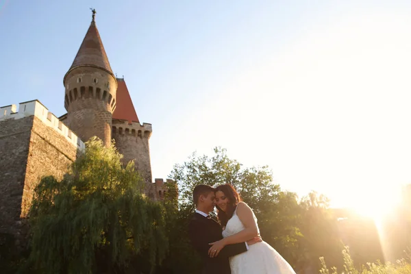 Жених и невеста обнимают средневековый замок в сумерках — стоковое фото