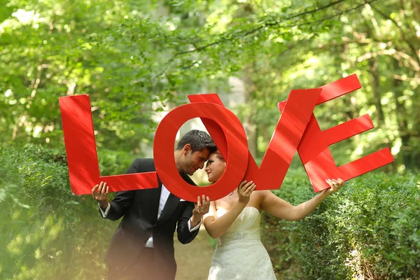 Beau couple nuptial dans les bois tenant des lettres d'amour — Photo