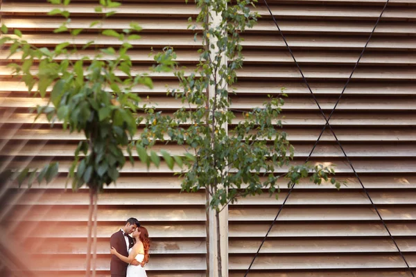 Schönes Brautpaar umarmt sich nahe entblößter Mauer — Stockfoto