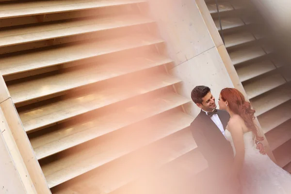 Belo casal nupcial abraçando perto de parede despojada — Fotografia de Stock