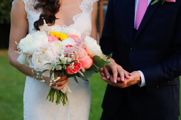 Noivo e noiva de mãos dadas e buquê de casamento — Fotografia de Stock