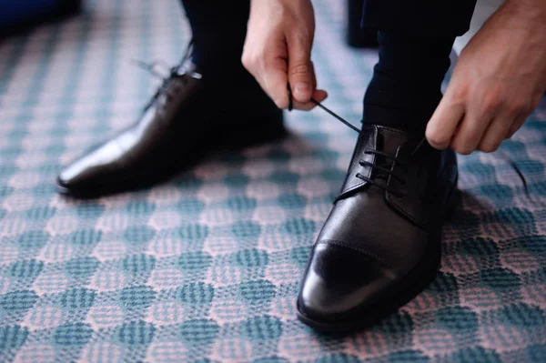 Man tying his black leather shoes