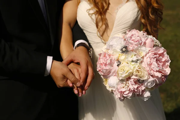 Νυφικό ζευγάρι κρατώντας τα χέρια και γαμήλια ανθοδέσμη — Φωτογραφία Αρχείου