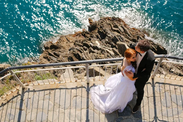 Sposo e sposa sulle rocce in riva al mare — Foto Stock