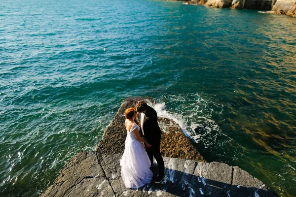 Brudgummen och bruden på klipporna vid havet — Stockfoto