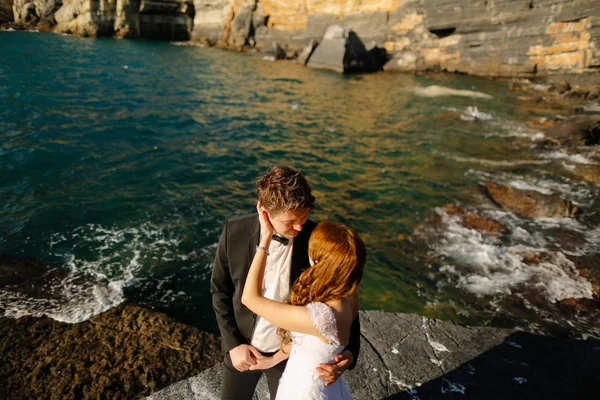 Groom and bride on the rocks by the sea — Stock Photo, Image