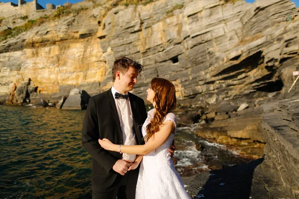 Groom and bride on the rocks by the sea — Stock Photo, Image